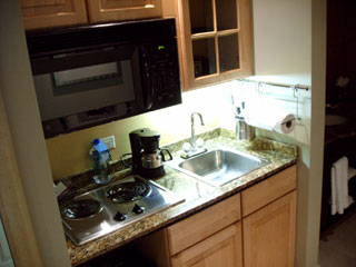 Magnolia Hotel suites include a kitchen area complete with microwave, burners, coffee maker, dishes, and silverware